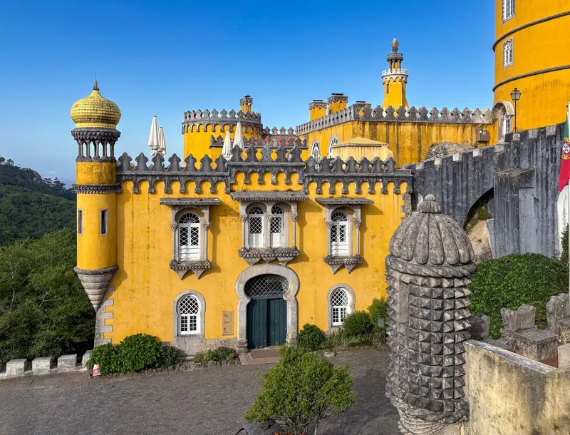 Fachada amarela do Palácio da Pena com merlões e janelas em arco, sob céu azul