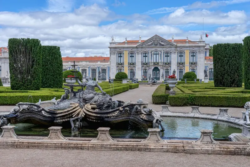 Fachada rosa e branca do Palácio Nacional de Queluz vista dos jardins formais